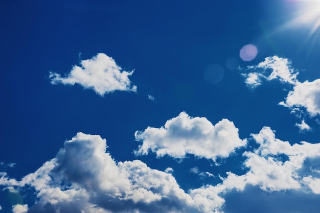 Beau ciel bleu foncé, nuages blancs et rayons de soleil. Fond de ciel