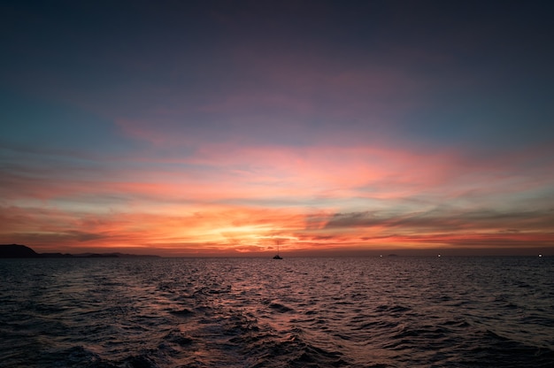 Beau ciel coucher de soleil sur la mer tropicale et bateau naviguant dans la soirée