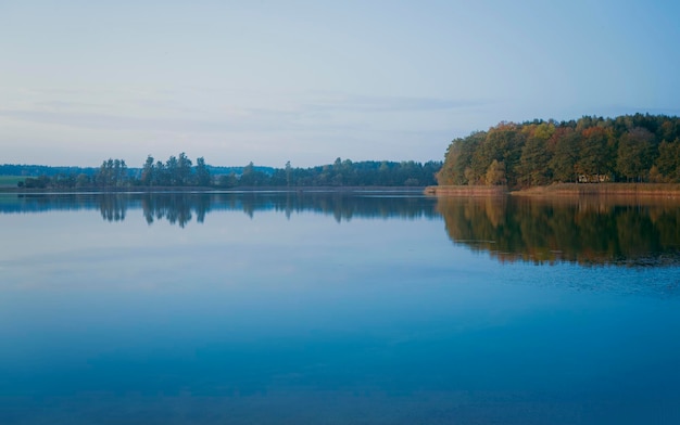 Beau ciel coucher de soleil avec des nuages au-dessus du lac Reflet du paysage d'automne dans l'eau