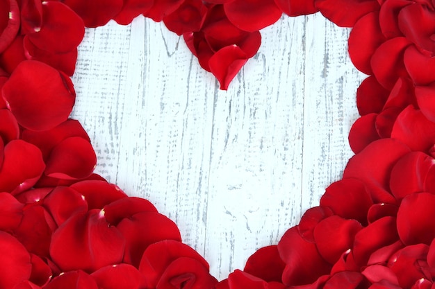 Beau coeur de pétales de rose rouges sur table en bois close-up
