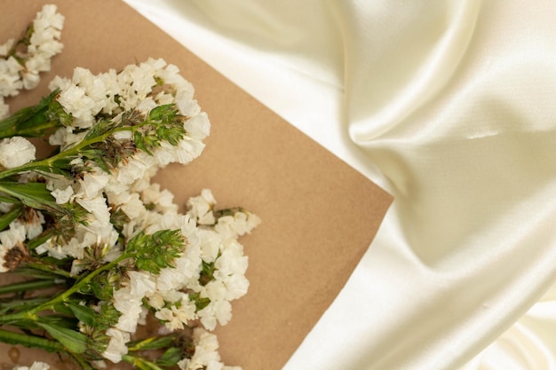 Beau concept de fleur Bouquet de statice en fleurs blanches avec du papier brun sur un tissu blanc