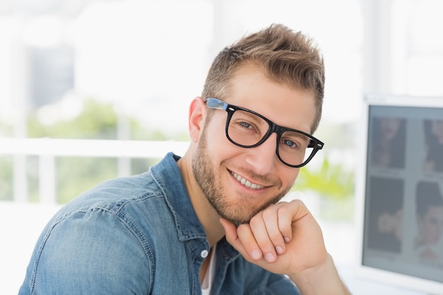 Beau concepteur souriant à la caméra à son bureau