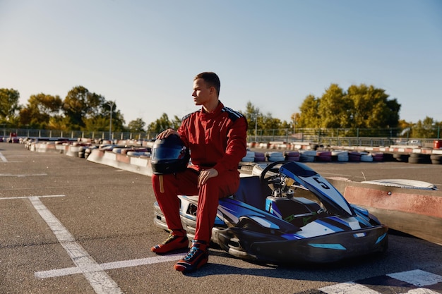 Un beau conducteur assis à sa voiture de gokart attendant le début de la compétition