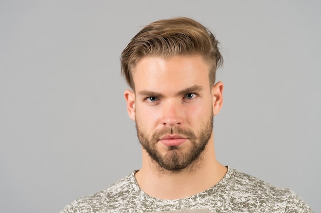 Beau et confiant. L'homme à la barbe non rasée bien entretenue a l'air beau et cool. Guy barbu attrayant se soucie de l'apparence. Soies de l'homme visage strict sérieux, fond noir se bouchent.