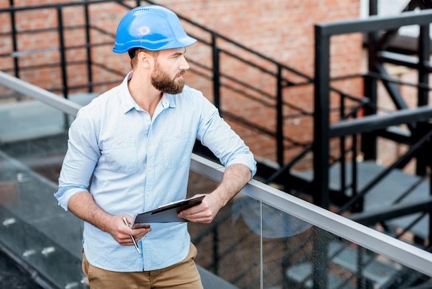 Beau contremaître ou constructeur en casque supervisant une nouvelle structure