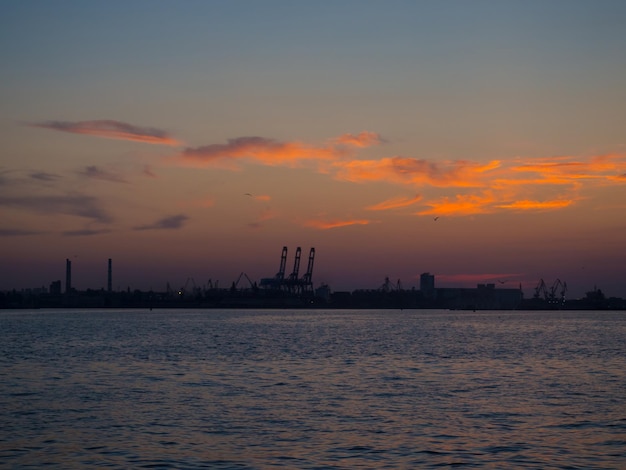 Beau coucher de soleil au-dessus du port avec des silhouettes de grues de fret Port industriel de la mer Noire Odesa Ukraine avec beaucoup de cabines de grues boîtes et réservoirs au bord de l'eau au crépuscule du soir