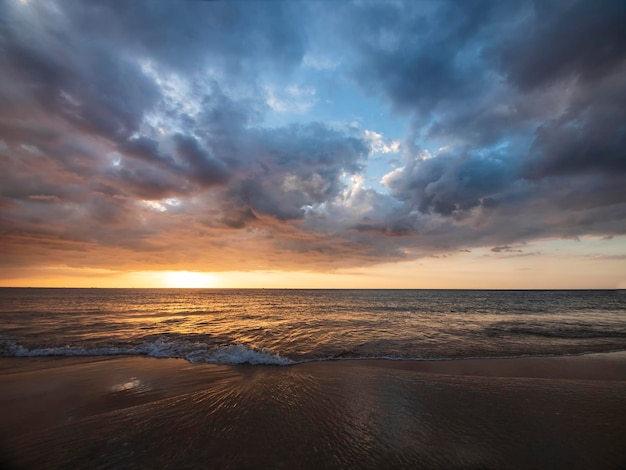 Beau coucher de soleil sur la mer calme avec fond de ciel nuageux. Coucher de soleil sur la plage tropicale. Concept d'été nature. Coucher de soleil de pointe sur la mer avec une lumière jaune réfléchie sur l'eau de mer. Paysage marin tranquille.