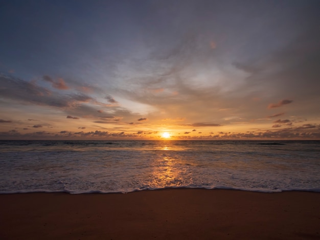 Beau coucher de soleil sur la mer calme avec fond de ciel nuageux. Coucher de soleil sur la plage tropicale. Concept d'été nature. Sommet du coucher de soleil sur la mer avec réflexion de lumière jaune sur l'eau de mer. Paysage marin tranquille.