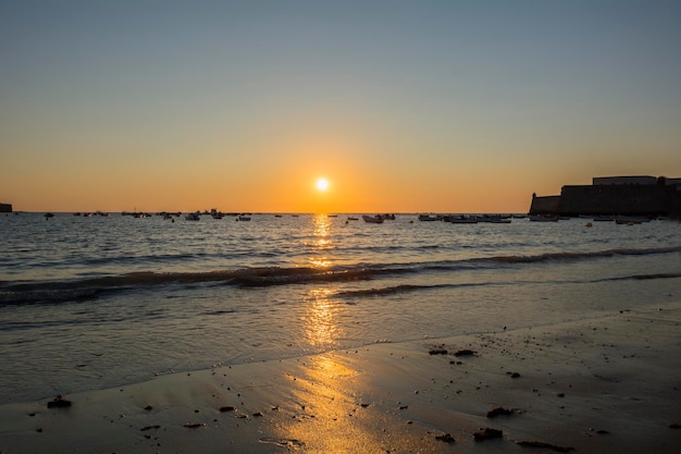 Beau coucher de soleil sur une plage avec des bateaux de pêche au fond de la plage de Caleta Cadix Espagne