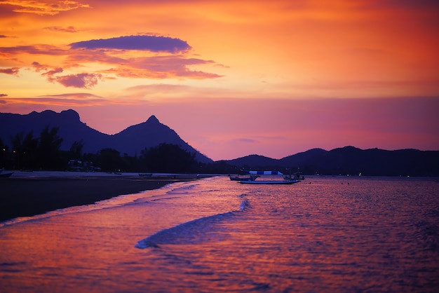 beau coucher de soleil sur la plage avec la silhouette du bateau