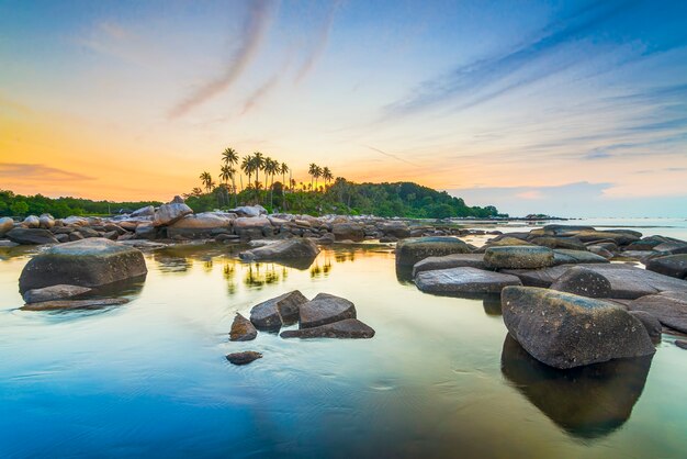 beau coucher de soleil avec des rangées de rochers et de cocotiers sur la côte de bintan indonésie