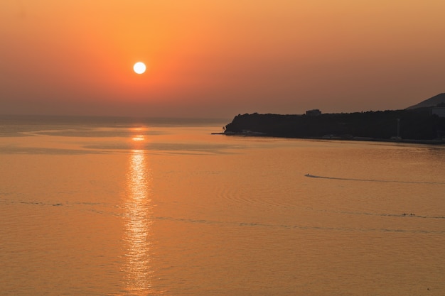 Beau coucher de soleil sans nuages sur la mer avec la lumière du soleil reflétée dans l'eau