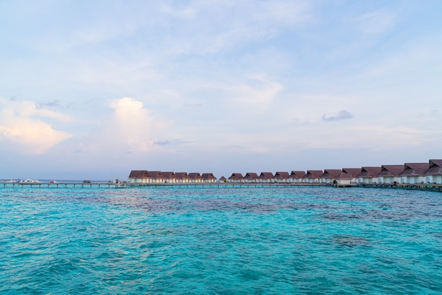 Beau coucher de soleil tropical sur l'île des Maldives avec bungalow sur l'eau dans un complexe hôtelier