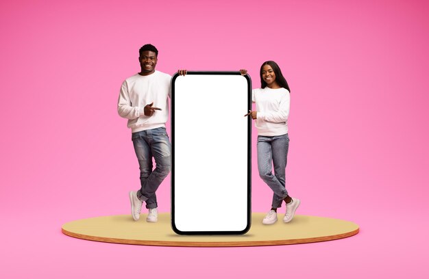 Beau couple afro-américain pointant sur un énorme téléphone