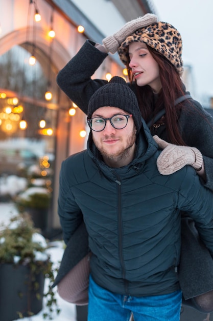 Un beau couple d'amants à la mode s'amusant en ville un bel homme portant une belle jeune femme sur son dos