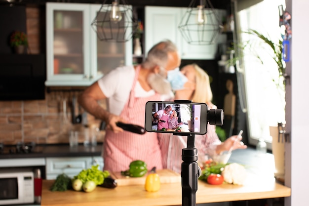 Beau couple amoureux blogueur cuisine en direct à la cuisine pour travailler à domicile. COVID-19 [FEMININE. Mise au point sélective.