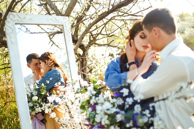 Photo beau couple d'amoureux dans les jardins fleuris. concept de mariage. grande lumière du coucher du soleil. beaux jeunes mariés