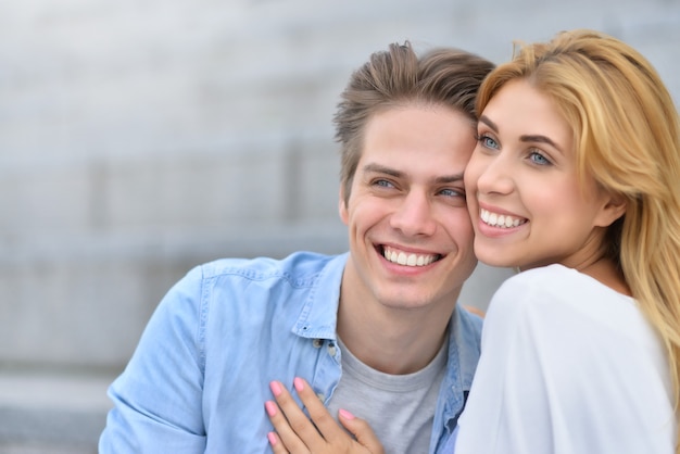 Beau couple amoureux datant à l'extérieur et souriant. La belle fille embrasse le gars