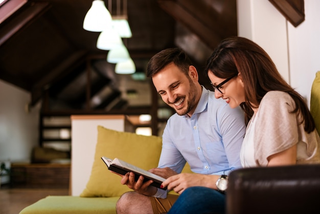 Beau couple d&#39;amoureux en lisant un livre sur le canapé