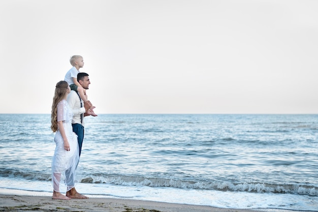 Beau couple amoureux marchant sur l'océan Voyage avec jeune enfant Bonne parentalité