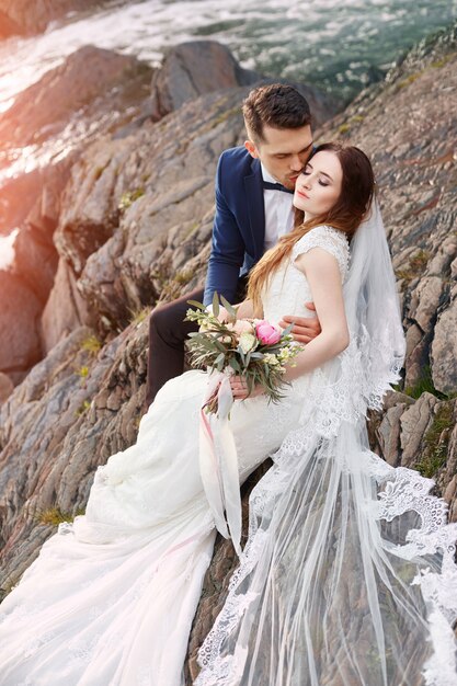 Beau couple amoureux s'embrasser assis sur des rochers