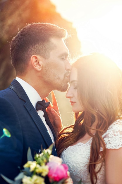 Beau couple amoureux s'embrasser en gros plan. Couple de mariage s'embrassant au coucher du soleil et des vagues d'amour et de tendres sentiments. Couple amoureux en vacances. Cérémonie de mariage en extérieur, couple parfait. Flou