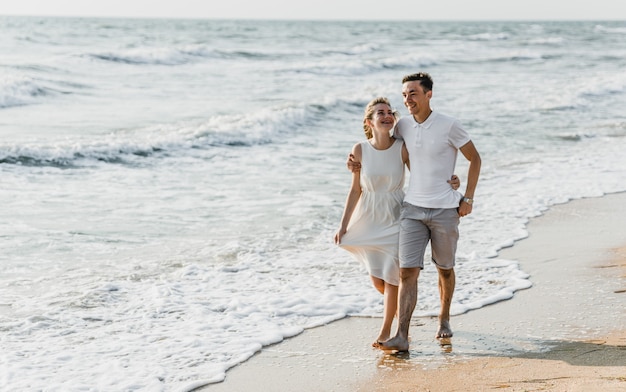 Beau couple d'amoureux se promène au bord de la mer. heureux jeune couple passe du temps sur la plage.