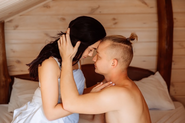 Un beau couple d'amoureux se regarde dans les yeux au lit