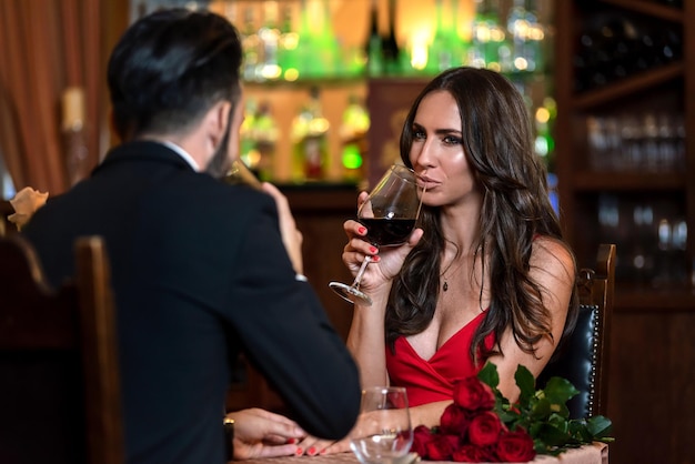 Un beau couple amoureux sort et boit du vin lors d'un dîner romantique au restaurant