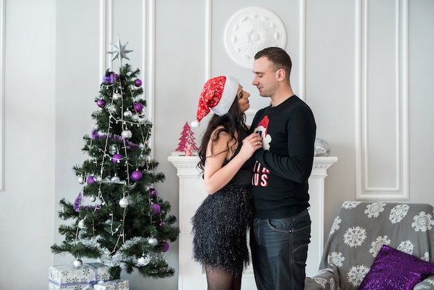 Beau couple avec arbre de Noël posant au studio