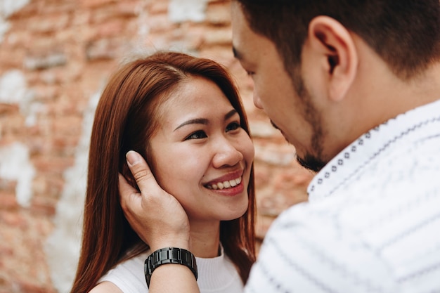 Beau couple asiatique par un mur de briques