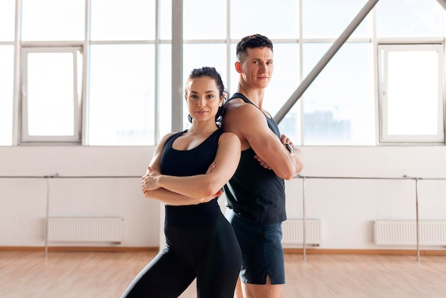 beau couple athlétique en vêtements de sport se tient dans la salle de sport le matin fille de fitness et entraîneur