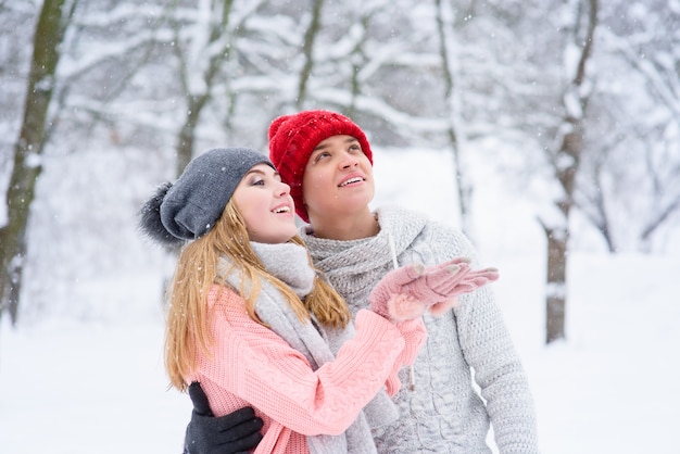 Beau couple attraper des flocons de neige à l'extérieur