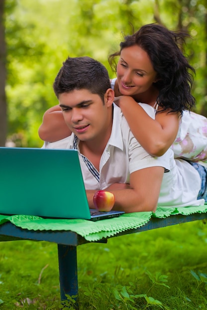 Beau couple sur banc avec ordinateur portable