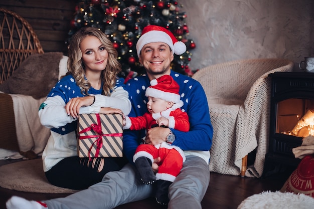 Beau couple et bébé admirable en costume de santa posant pour un portrait de famille de concept de Noël. Concept de vacances
