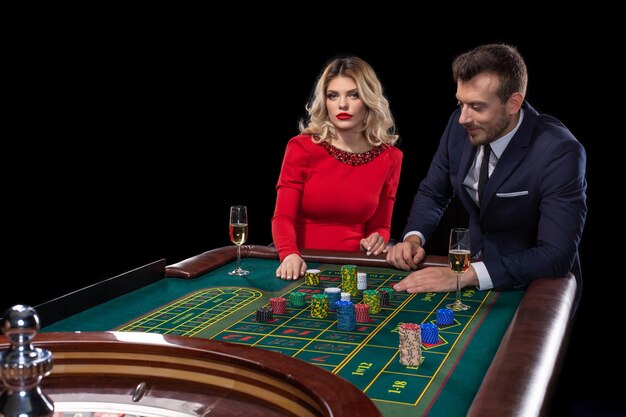 Beau couple bien habillé jouant à la roulette au casino