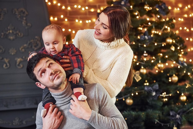 Beau couple caucasien célébrant Noël à l'intérieur avec leur petit fils.