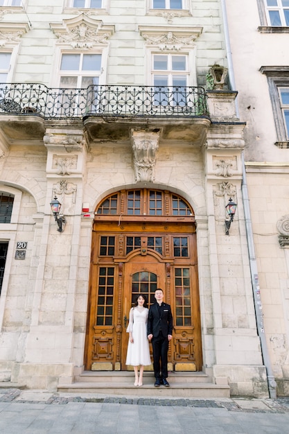 Beau couple chinois posant près de la porte brune antique de l'ancien bâtiment historique dans la vieille ville européenne