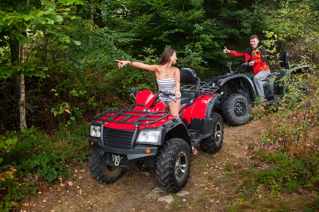 Beau couple conduisant un VTT à quatre roues et se regardant.