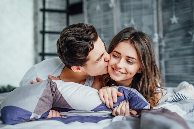 Beau couple dans leur chambre et s'embrasser. Assis sur le lit