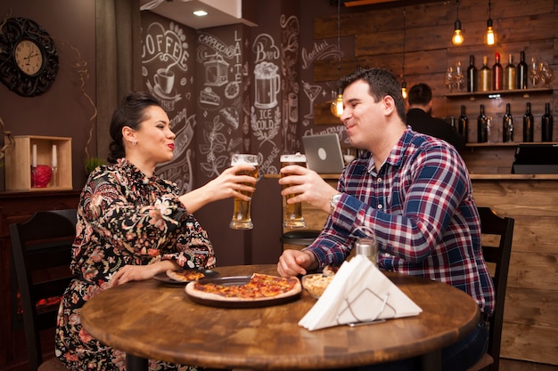 Beau couple dans un nouveau pub appréciant leur bière. Pub branché.