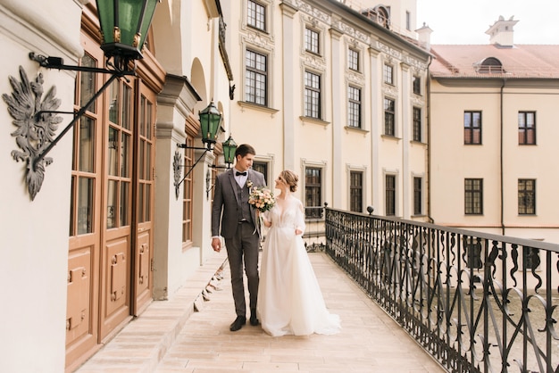 Beau couple élégant de jeunes mariés amoureux sur vieux bâtiment et pavés, mariage européen