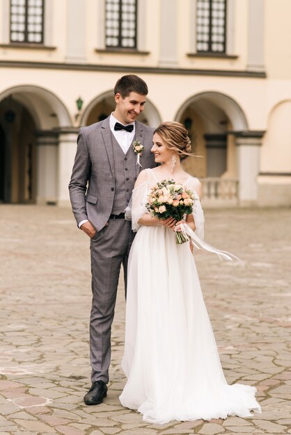 Beau couple élégant de jeunes mariés amoureux sur vieux bâtiment et pavés, mariage européen