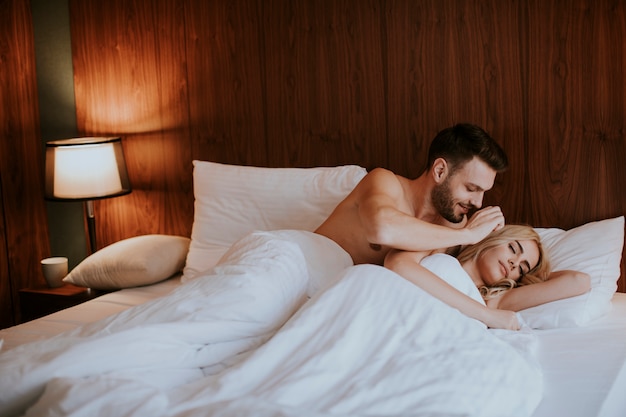 Beau couple embrassant sur leur lit à la maison