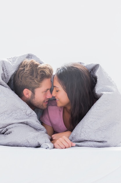 Beau couple enveloppé dans la couette