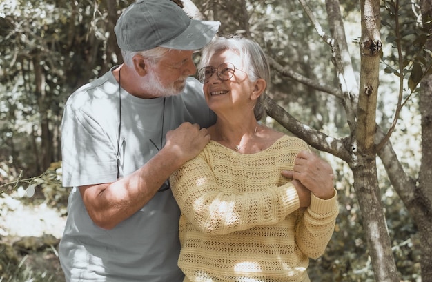 Beau couple de famille senior souriant étreignant à l'extérieur en profitant d'une randonnée en montagne dans les bois