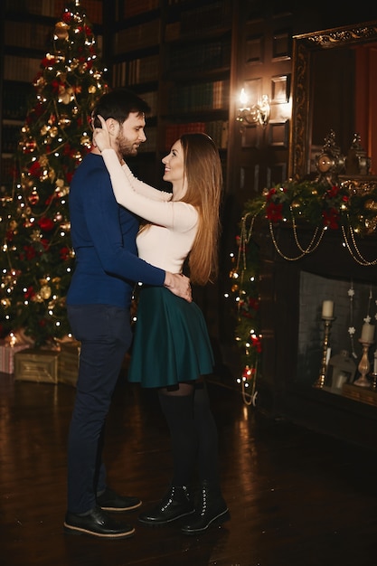 Beau couple, femme modèle une jupe dans une étreinte d'un bel homme barbu près de l'arbre de Noël