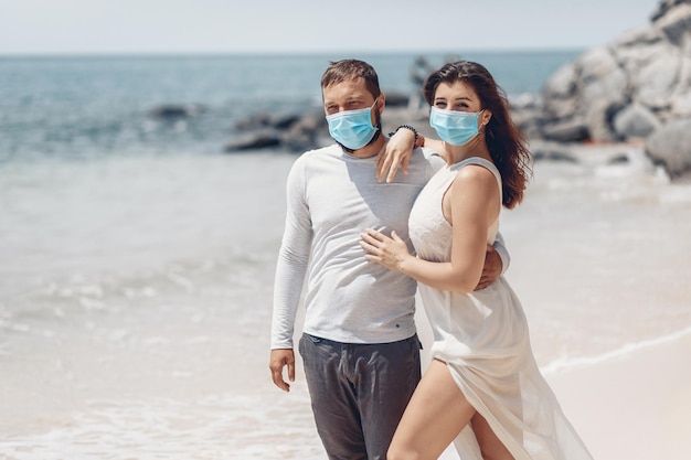 Beau couple à des fins d'hygiène personnelle mettant des masques médicaux sur leur visage pour se protéger d'une infection à coronavirus. Notion COVID-19