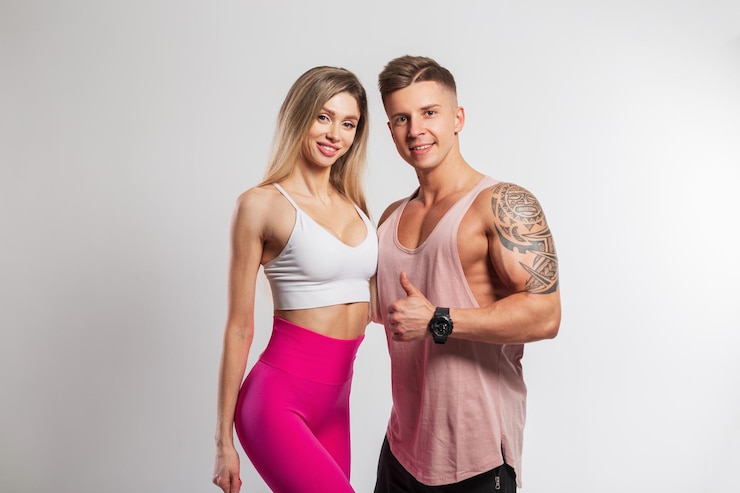 Photo beau couple de fitness heureux en bonne santé sur fond blanc belle dame de remise en forme avec sourire et beau mec musclé en vêtements de sport dans le studio
