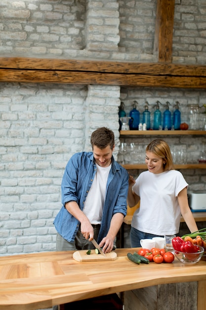 Beau couple gai, cuisiner ensemble et s&#39;amuser à la cuisine rustique